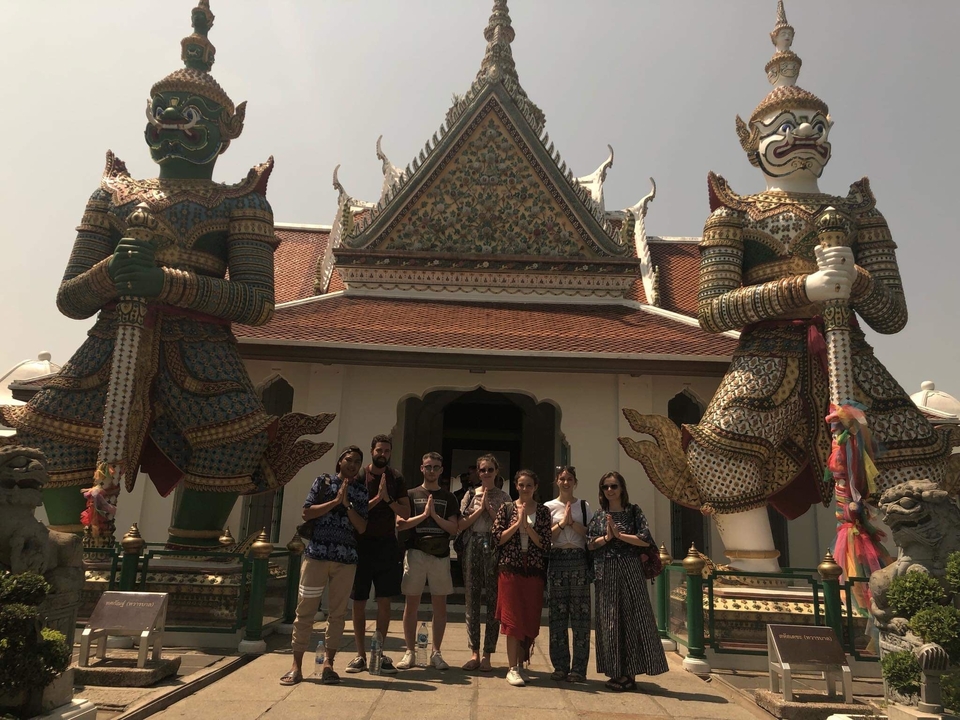 Group of people posing in front of a temple with statues.