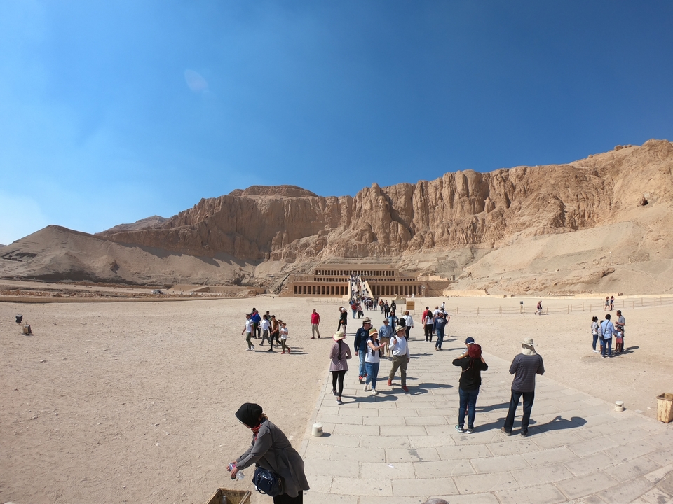 Touristes marchant vers un site historique dans un paysage désertique