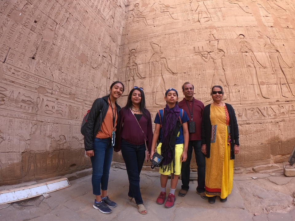 Famille posant devant des murs sculptés sur un site de l'Égypte antique