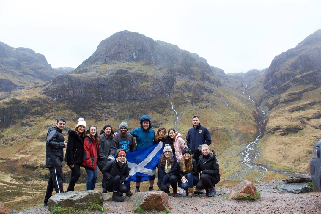 Group of people holding a flag in front of mountains.