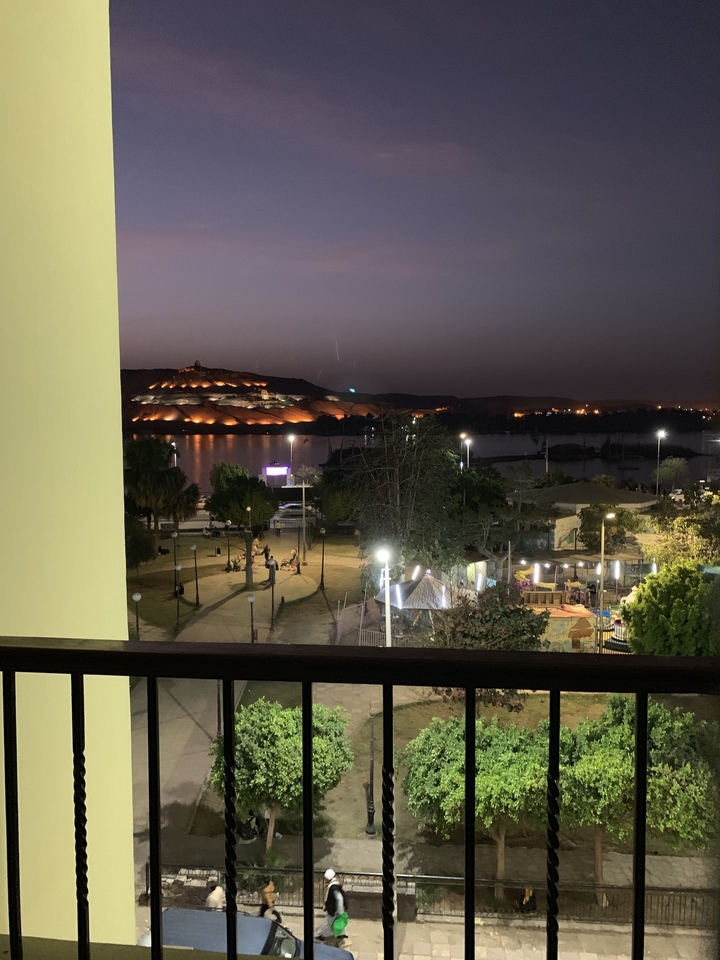 Vue nocturne d'Assouan avec des structures illuminées de l'autre côté du Nil.