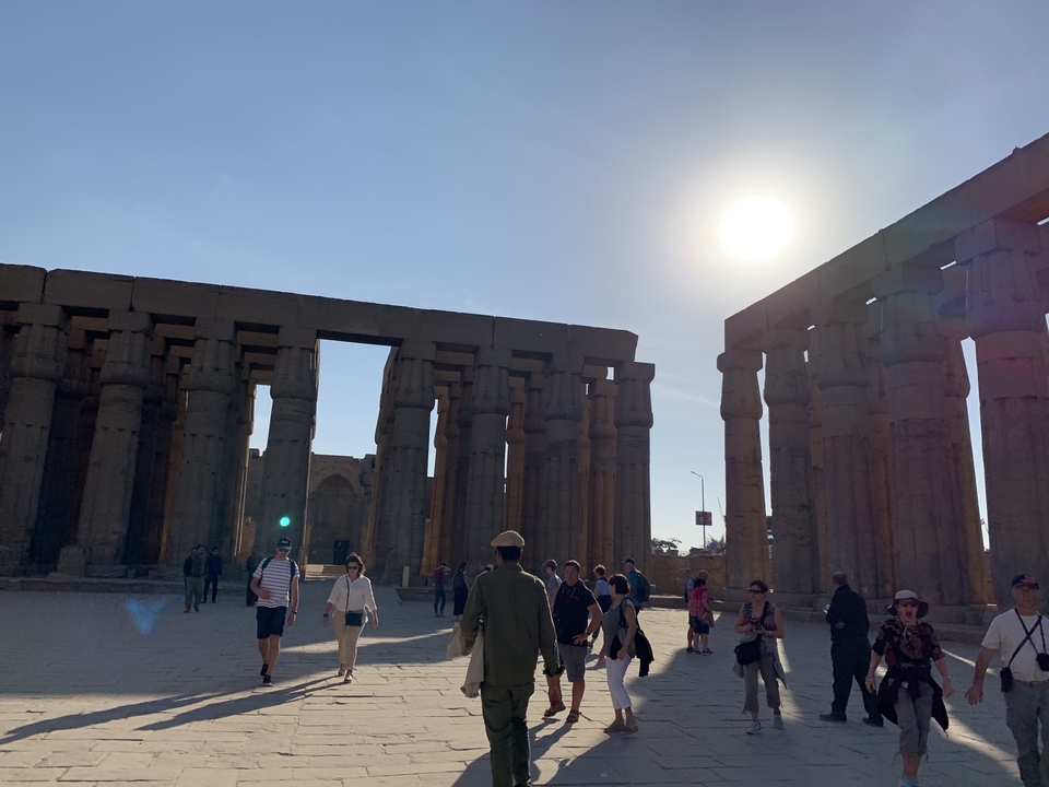Visiteurs se promenant à travers un ancien temple sous un soleil éclatant.