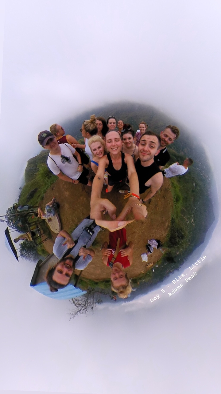 Selfie de groupe à un point de vue au sommet d'une colline avec des collines brumeuses.