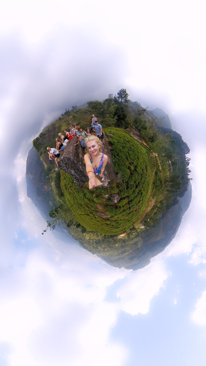 Selfie avec une vue panoramique d'un paysage vallonné verdoyant.