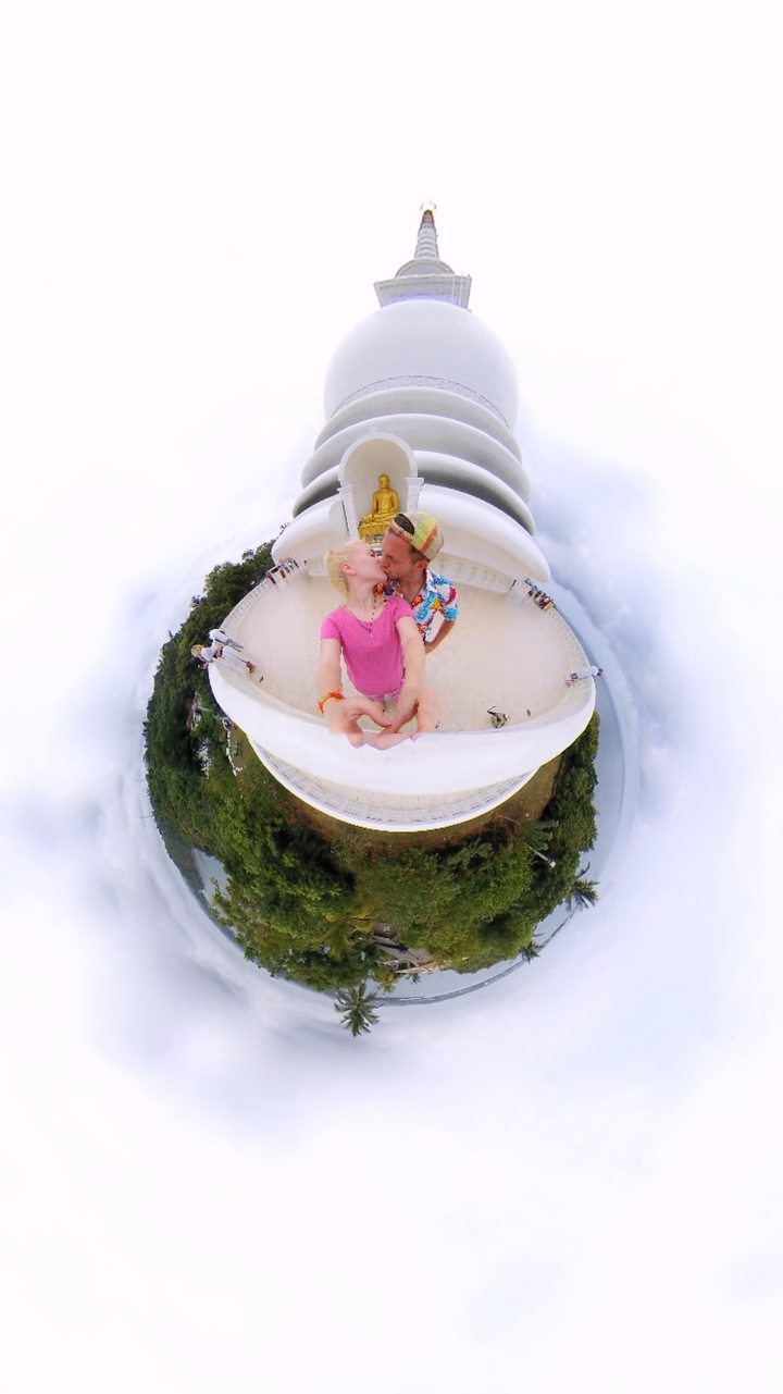 Couple posant sur une structure blanche éclatante entourée de verdure.