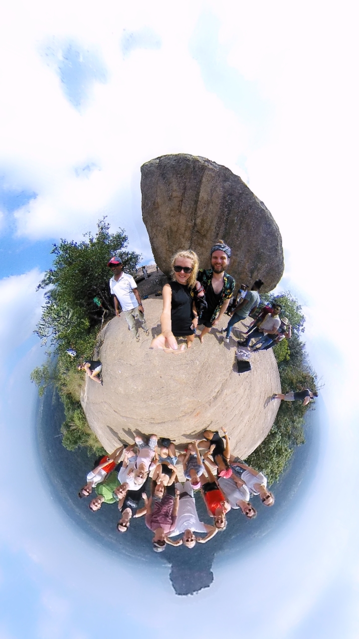 Selfie de groupe au bord d'une falaise rocheuse avec des arbres épars.