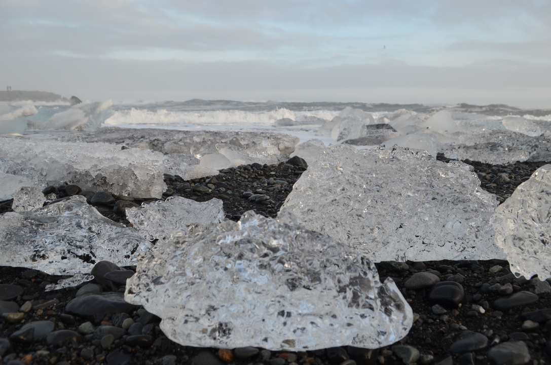 Des morceaux de glace sur une plage de sable noir avec des vagues.