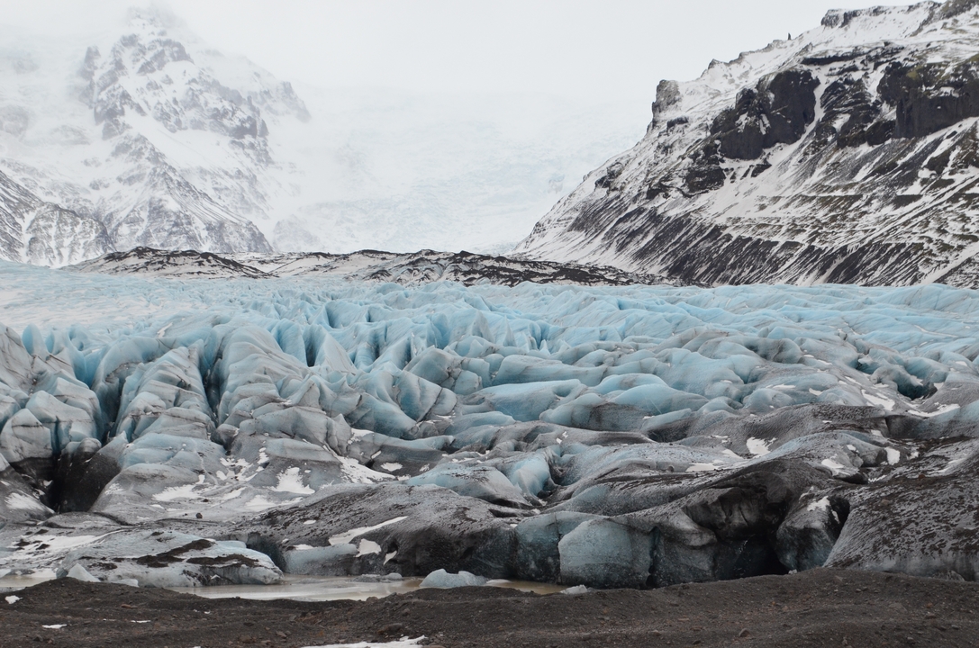 Vue large d'un glacier déchiqueté avec des sommets enneigés en arrière-plan.