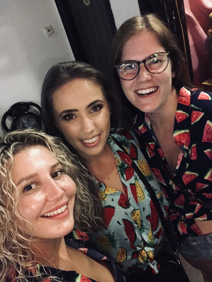 Gros plan de trois femmes souriantes portant des vêtements à motifs de fruits.