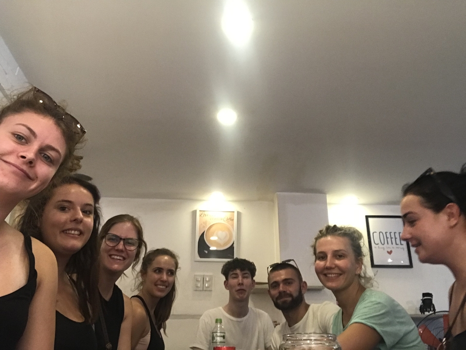 Groupe de personnes assises à l'intérieur, souriant à la caméra.