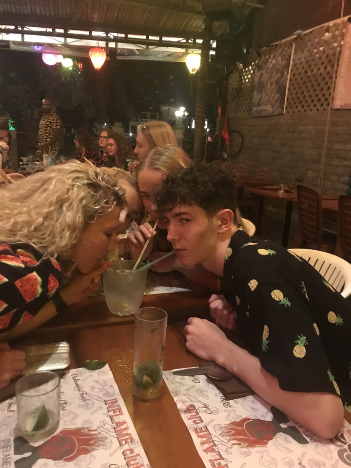 Groupe de personnes buvant dans un verre partagé avec des pailles.
