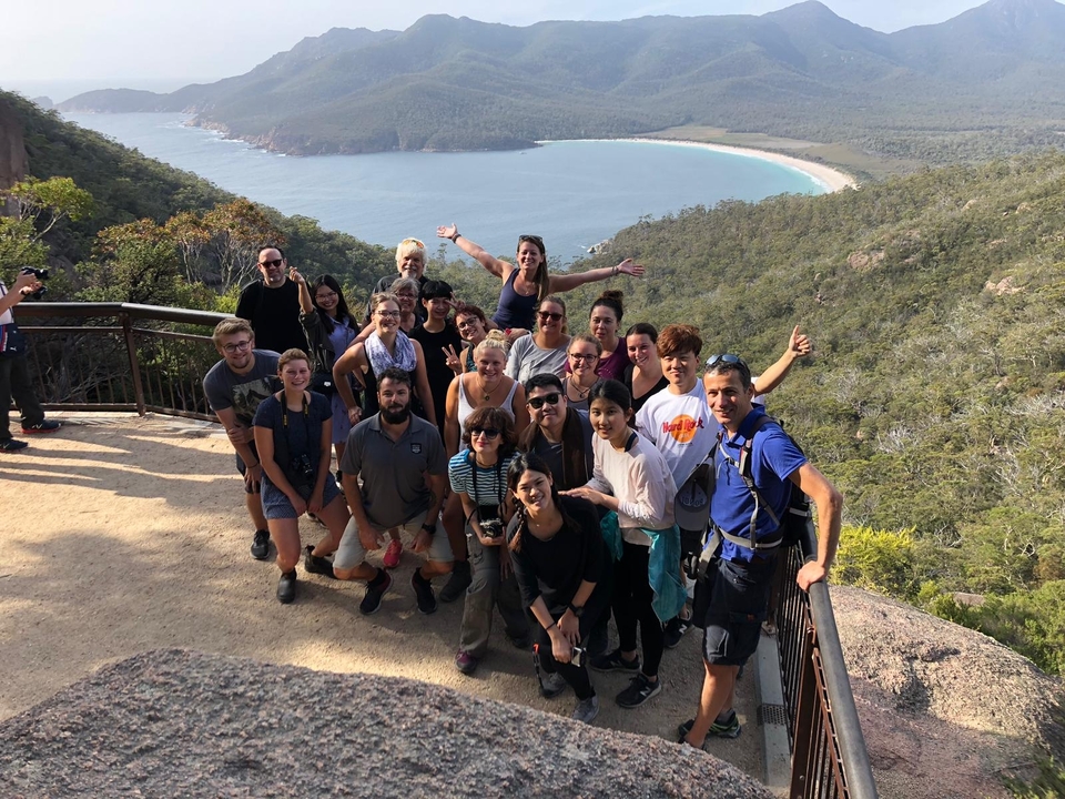 Un groupe de personnes posant à un point de vue donnant sur une baie entourée de montagnes.