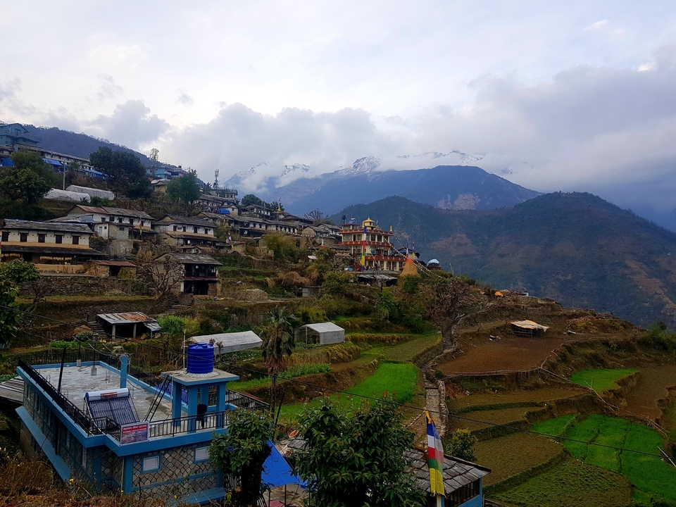 Un village de montagne avec des champs en terrasses et des sommets lointains.