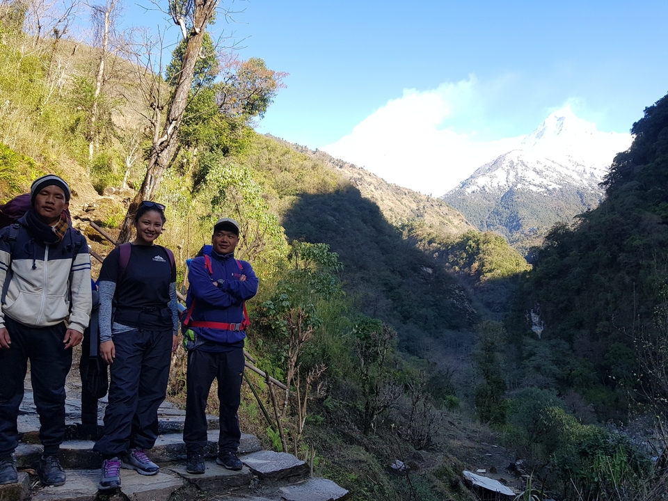 Trois randonneurs debout sur un sentier avec une vue panoramique sur la montagne.