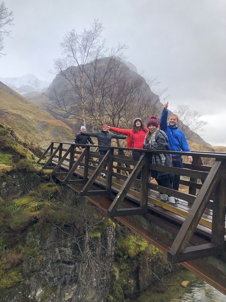 Groupe de randonneurs posant sur un pont en bois dans un paysage rural.
