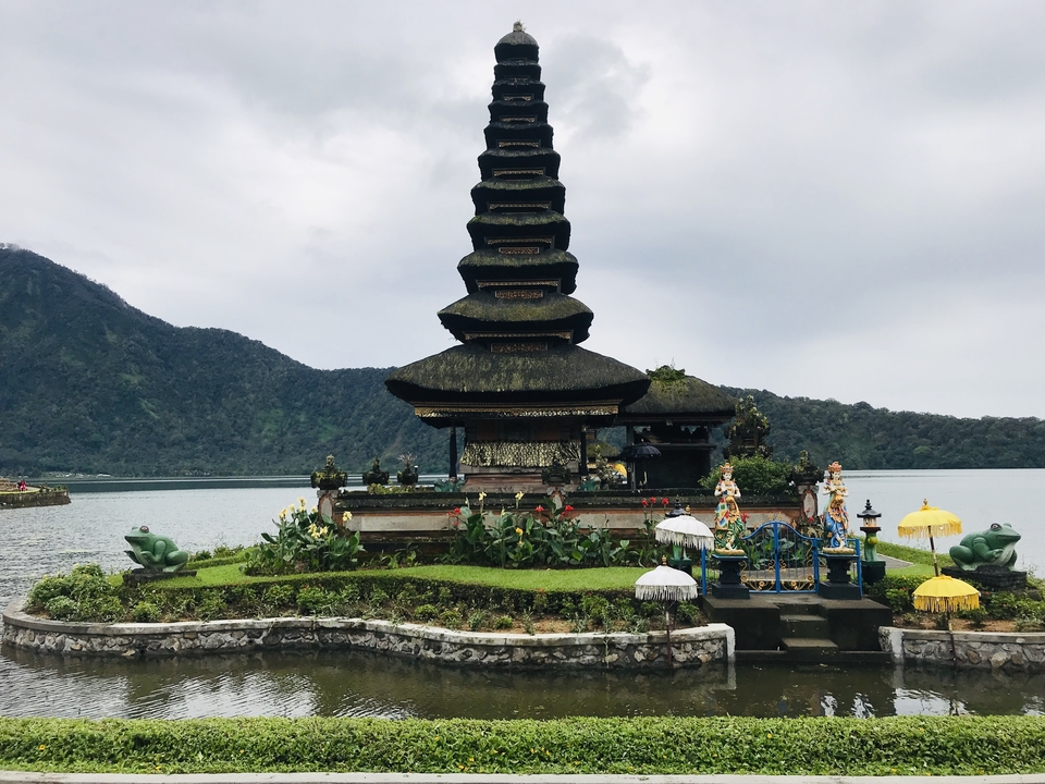Temple de l'eau au bord d'un lac avec des montagnes en arrière-plan.