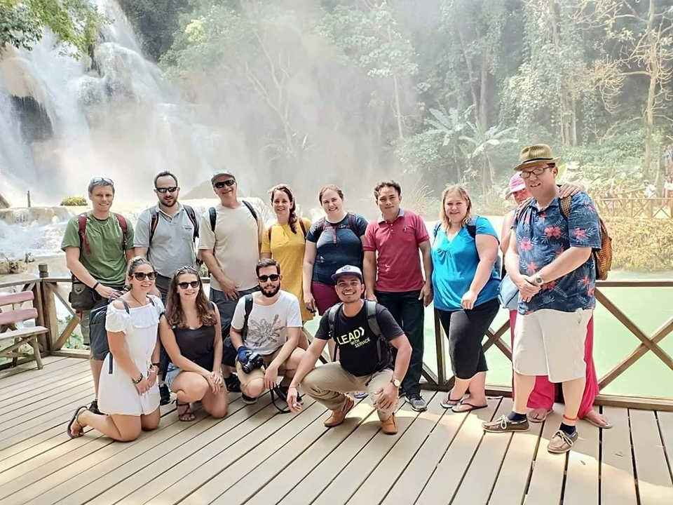 Groupe de personnes posant près d'une cascade.