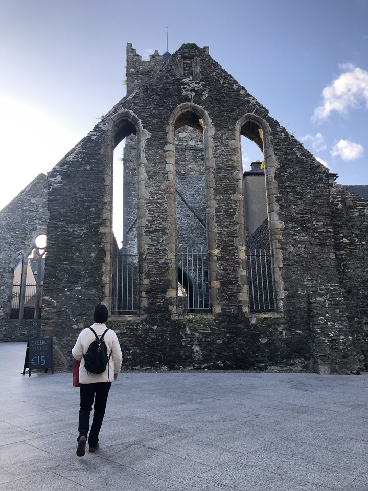 Une personne debout devant des ruines avec des murs de pierre.