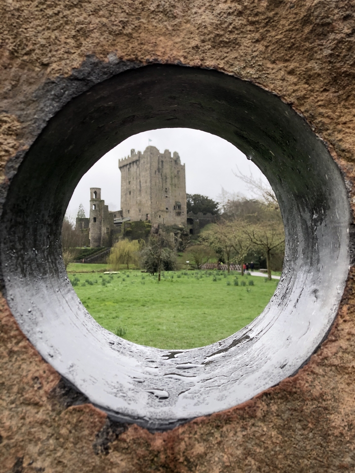 Une vue à travers une ouverture circulaire vers le château de Blarney.