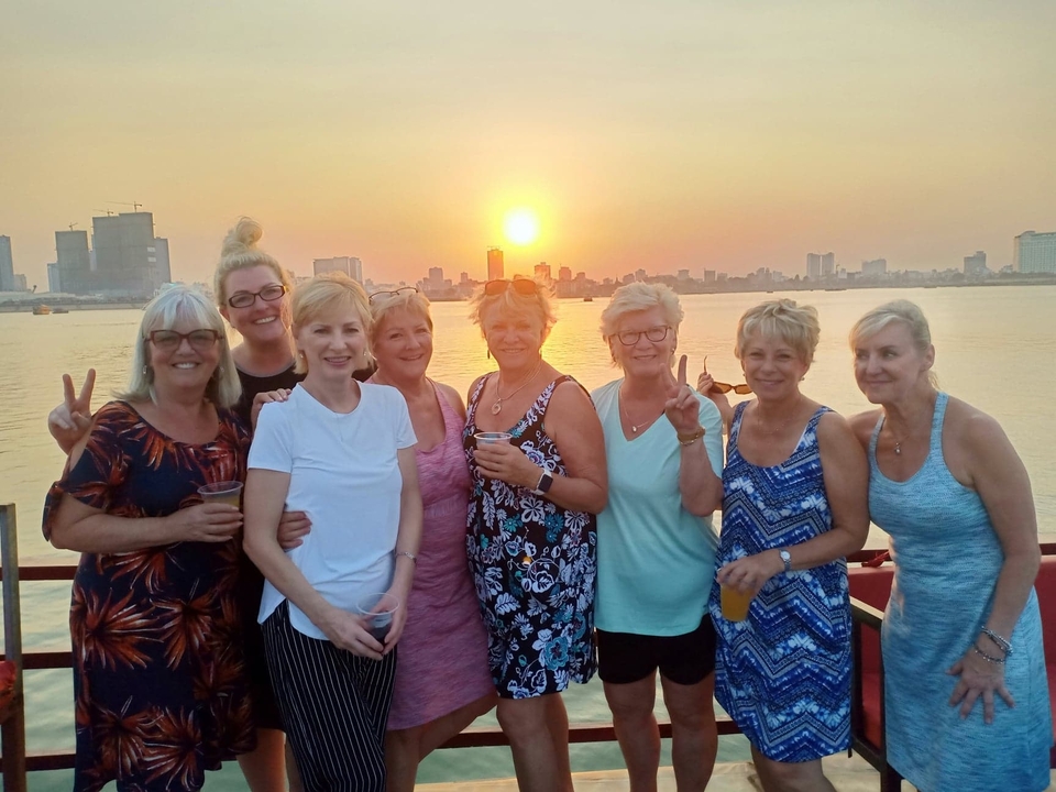 Un groupe de femmes posant avec un coucher de soleil sur l'horizon d'une ville.