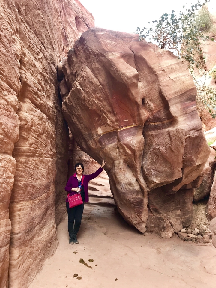 A person posing near rock formations.