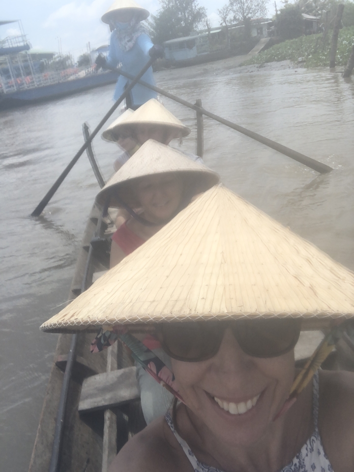 Une personne portant un chapeau conique dans un bateau sur une rivière.