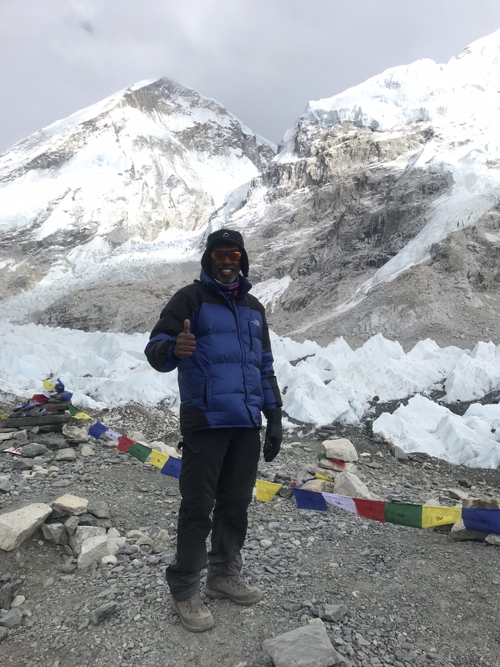 Un homme qui pose avec le pouce levé dans une région montagneuse enneigée.