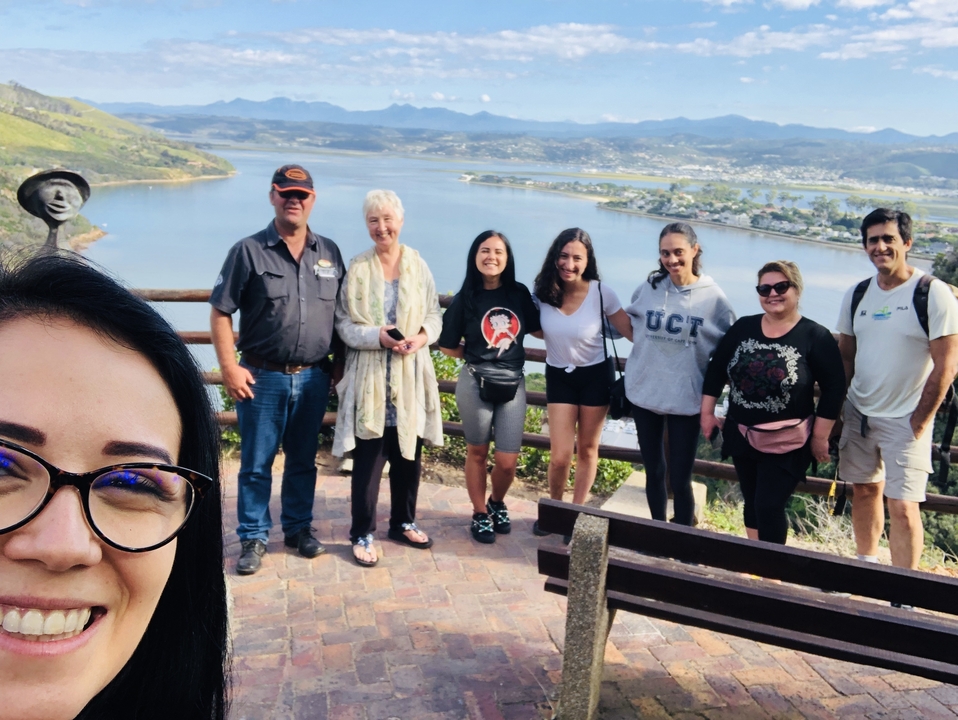 Groupe de personnes posant avec une vue panoramique sur un lac et des montagnes.