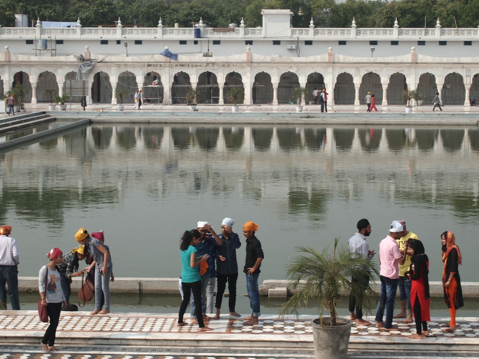 Des gens rassemblés près d'un bassin réfléchissant à côté d'un bâtiment historique.