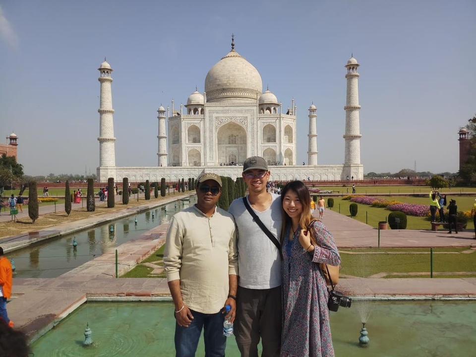 Travellers posing in front of the iconic Taj Mahal and reflecting pool.