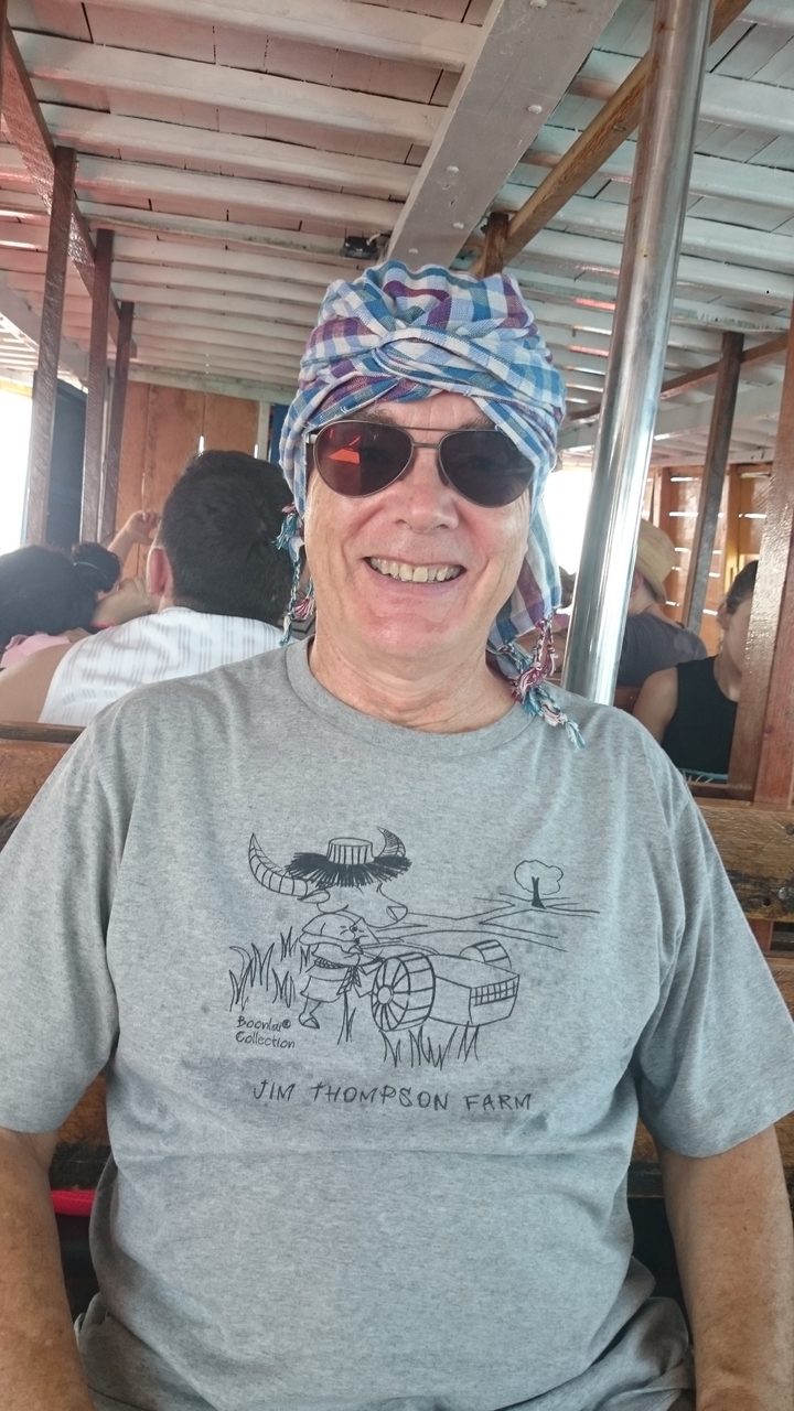 Une personne qui sourit à l'intérieur avec des gens en arrière-plan.