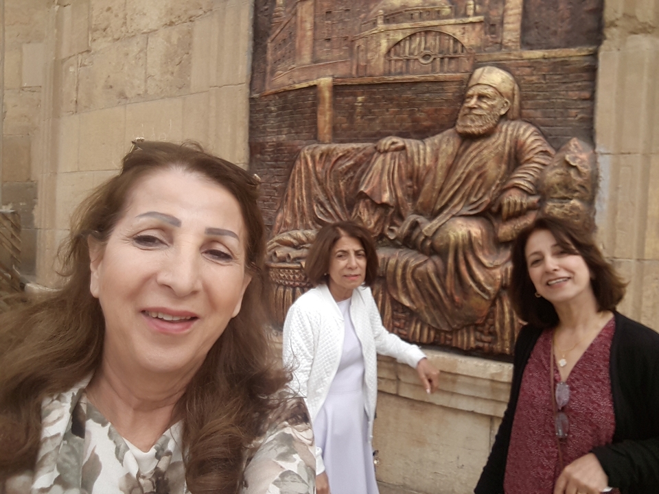 Trois femmes posant devant une statue de bronze.