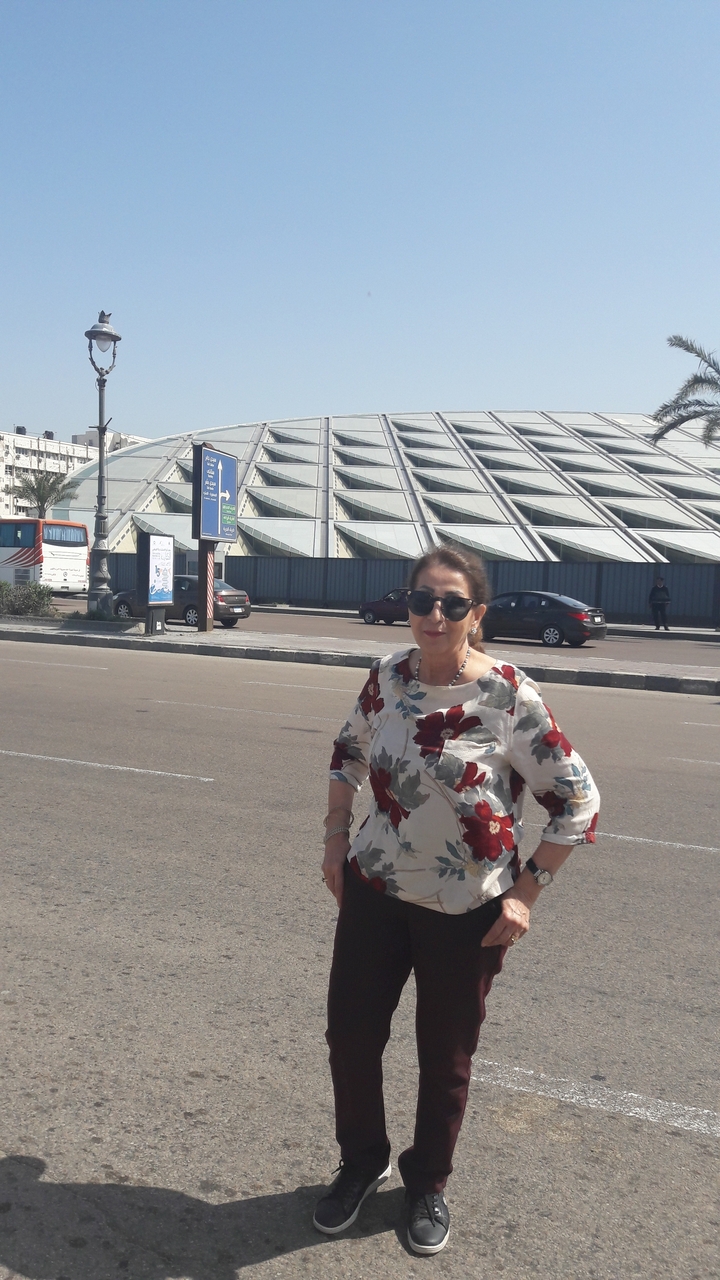 Une femme debout devant un bâtiment moderne au design géométrique.