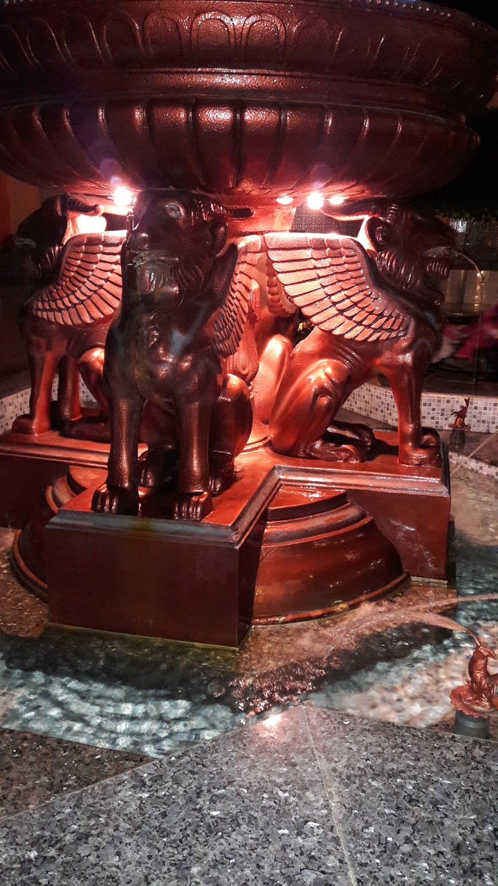 Gros plan d'une sculpture de lions ailés dans une fontaine.