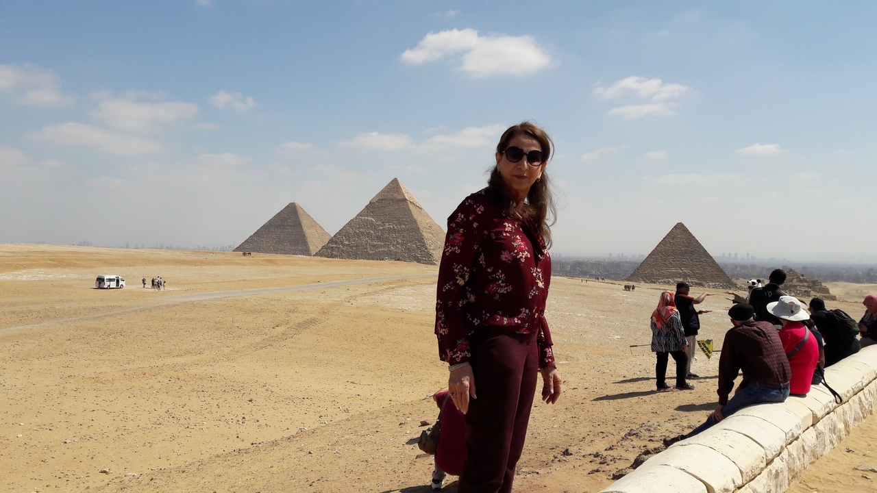 Une femme debout devant les pyramides de Gizeh.
