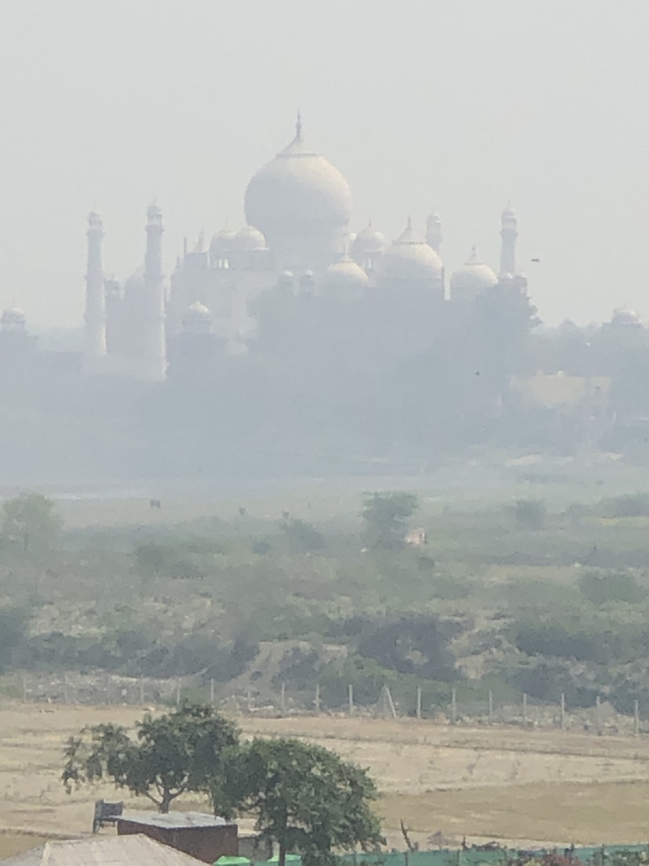 Une vue brumeuse et lointaine d'un grand bâtiment, possiblement le Taj Mahal.