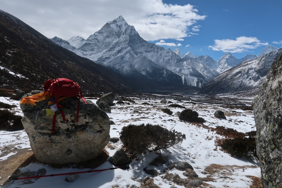 Sac à dos rouge sur un rocher avec des montagnes enneigées en arrière-plan.