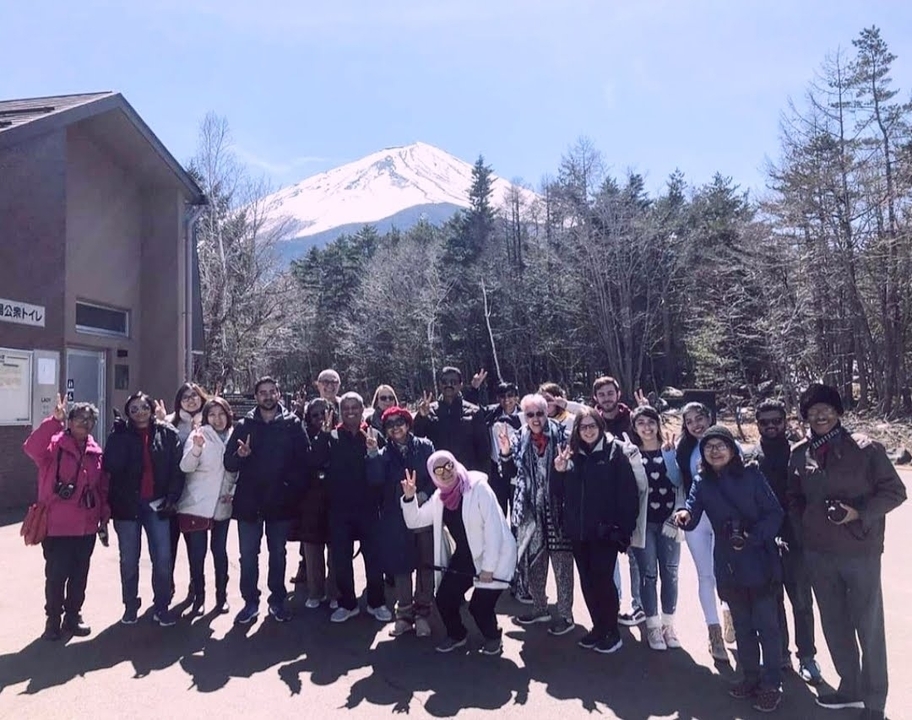 Group of tourists posing with a mountain in the background.