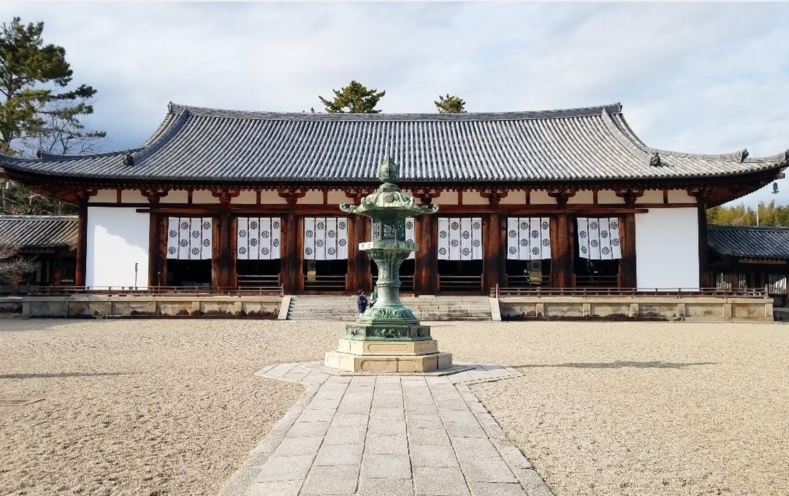 Traditional Japanese temple with a statue in front.