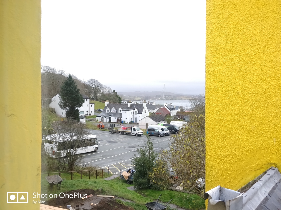 Vue d'un petit village avec un parking et des collines environnantes.