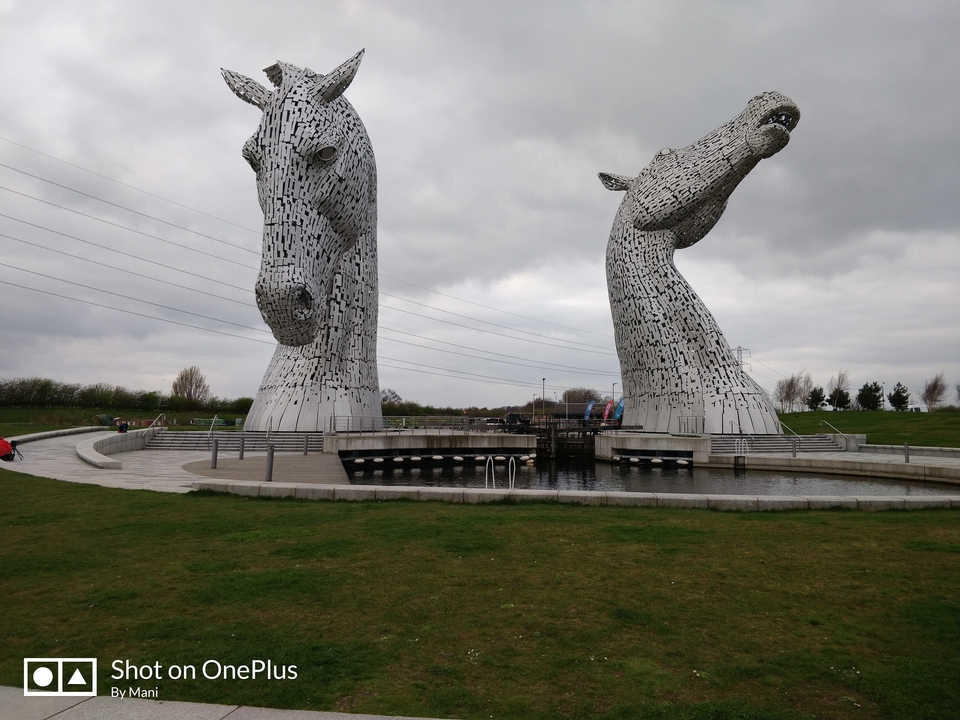 Les sculptures des Kelpies dans une zone herbeuse avec un ciel couvert.