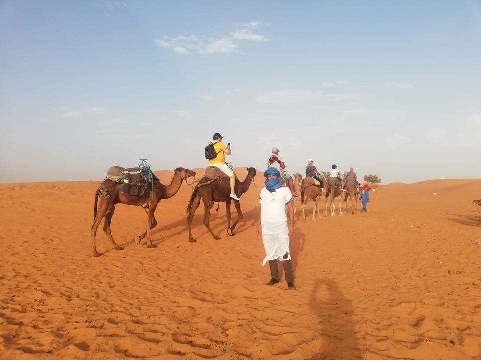 People riding camels on sand dunes.