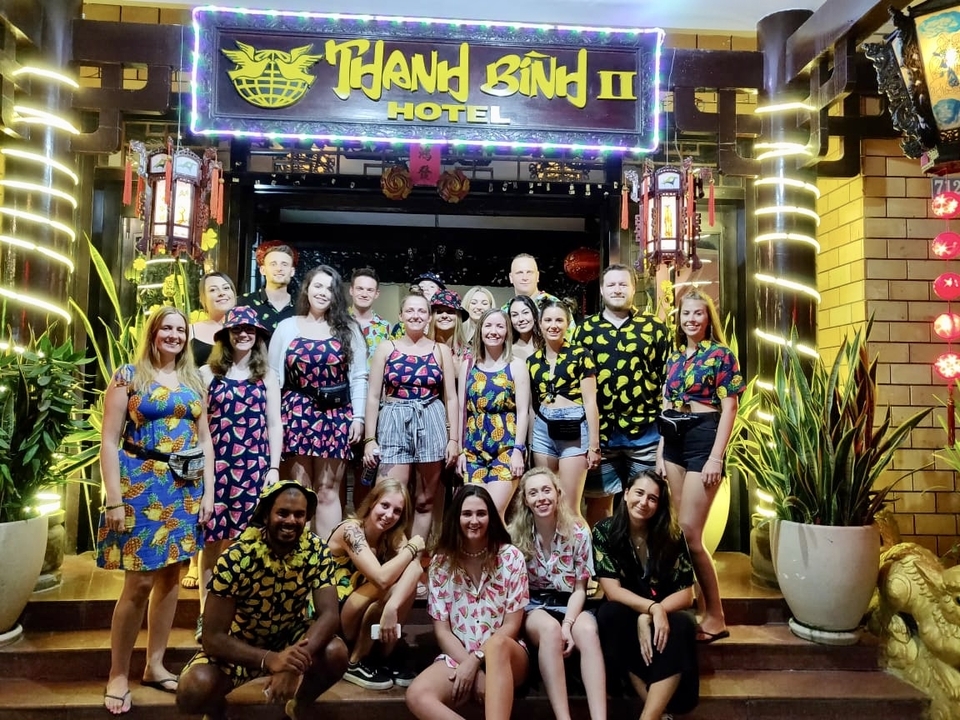 Group of people outside a hotel at night wearing colorful shirts.