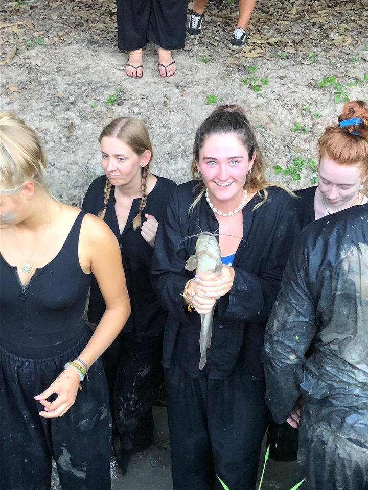 Personne tenant un poisson avec d'autres à proximité.