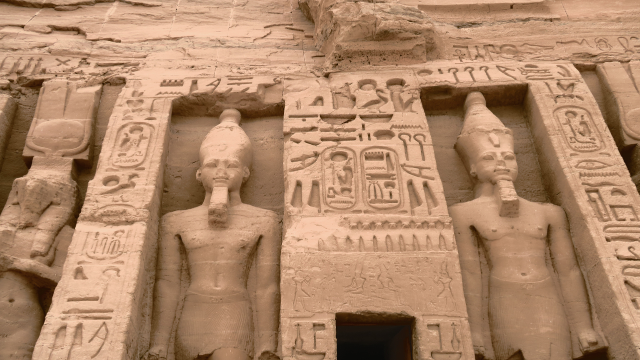 Statues et hiéroglyphes sur le mur d'un temple antique.