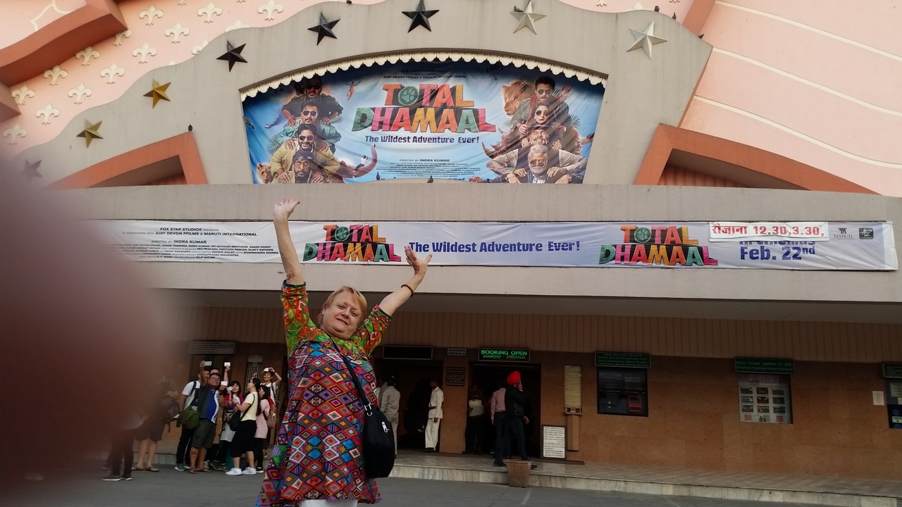 Personne posant avec enthousiasme devant un cinéma.