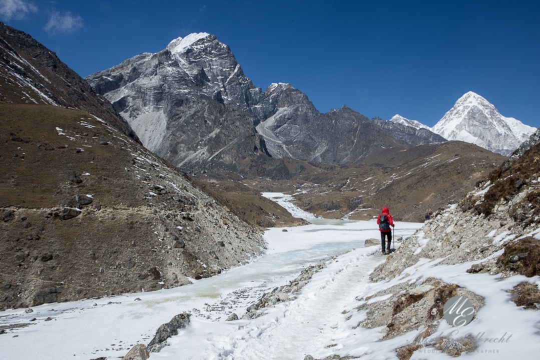 Personne marchant le long d'un sentier de montagne enneigé avec un terrain escarpé.