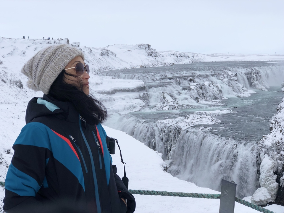 Person standing by a snowy waterfall