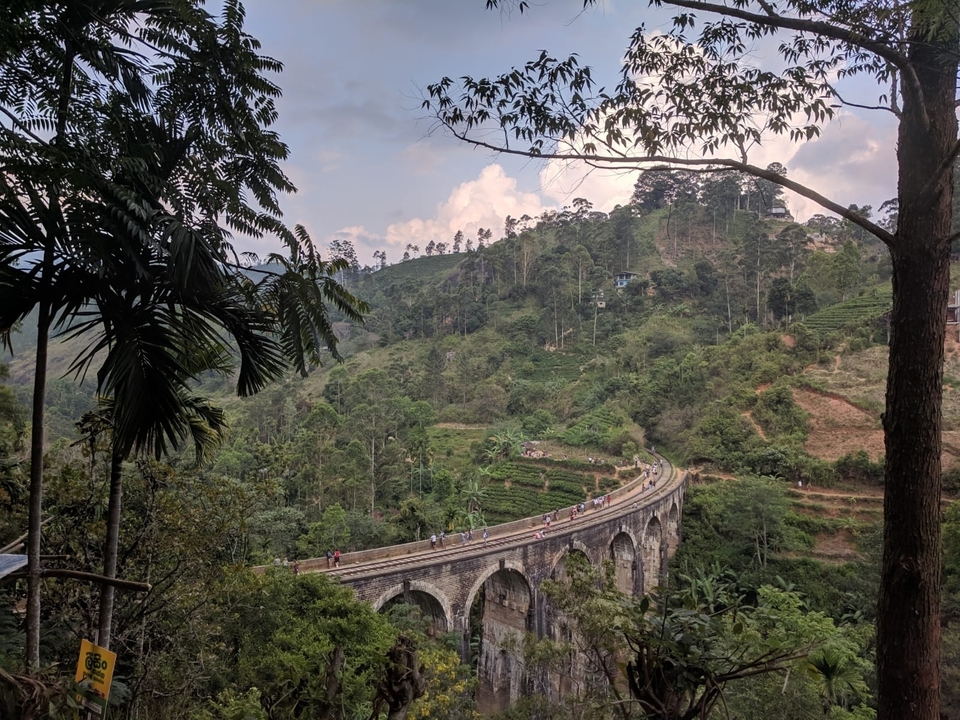 Vue du pont depuis une colline verdoyante avec des personnes qui marchent.