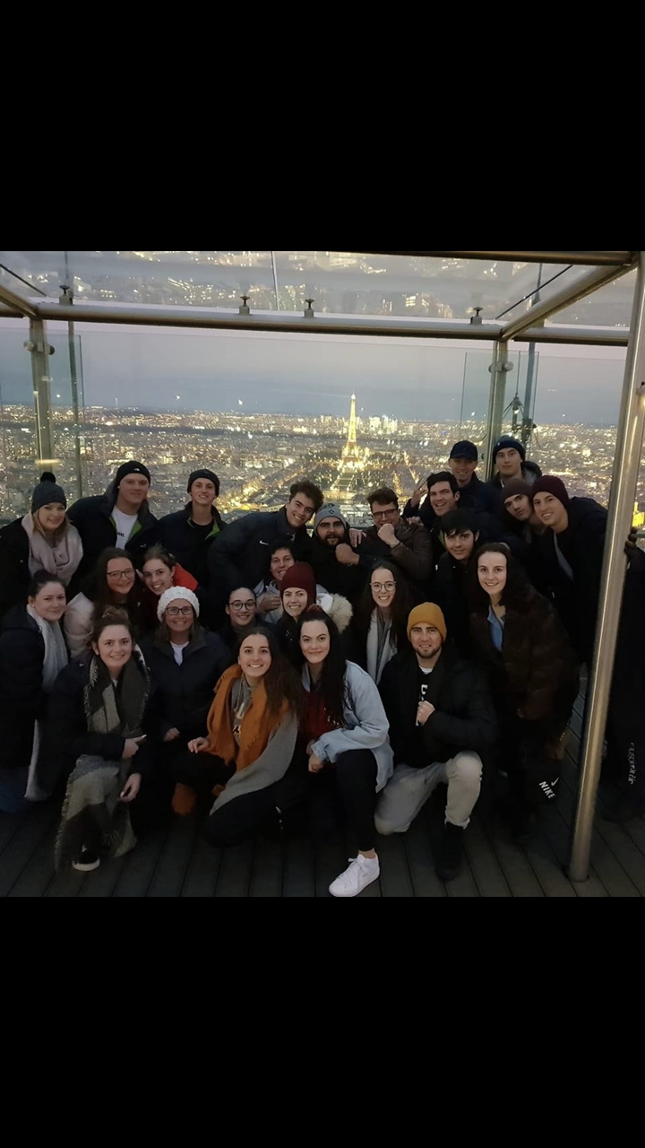 Grand groupe de personnes posant avec les lumières de la ville en arrière-plan.